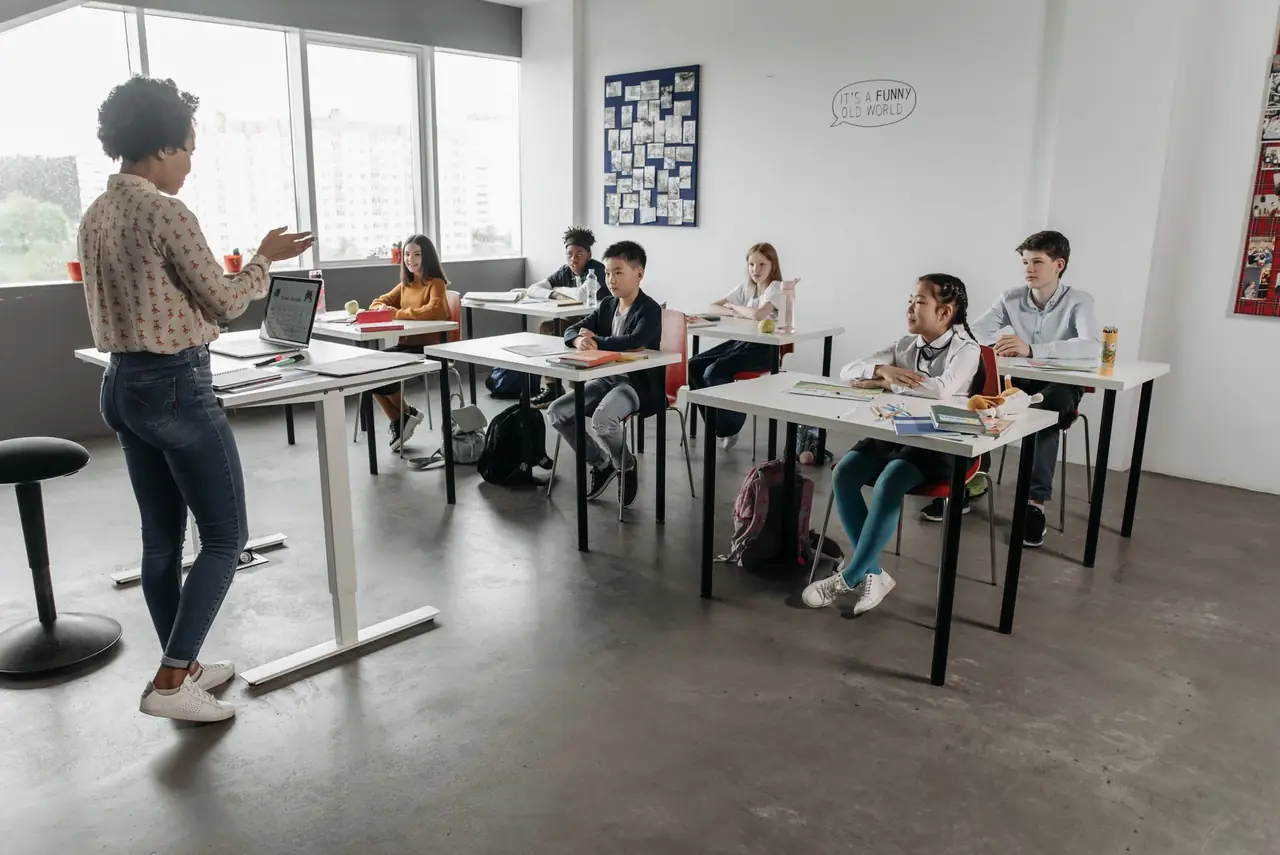 Teacher speaking with students seated at classroom desks